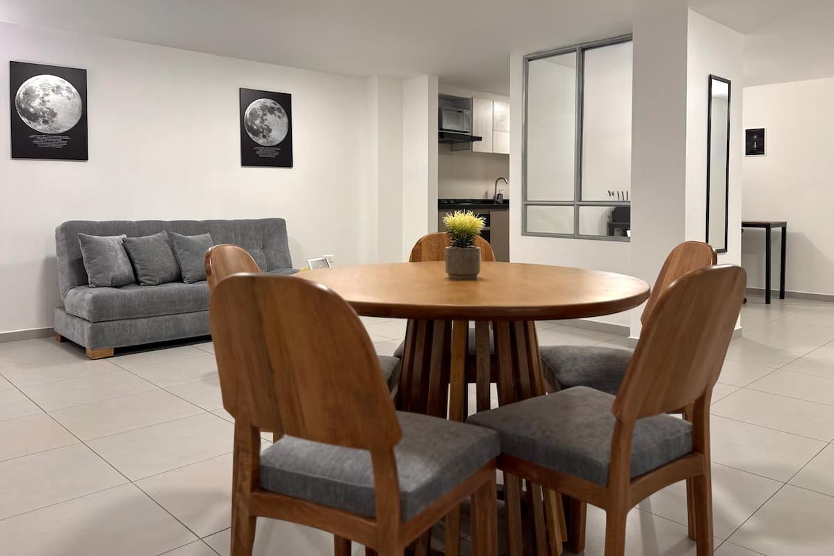 Sala comedor con sofá gris, mesa redonda de madera y cuadros de la luna en la pared