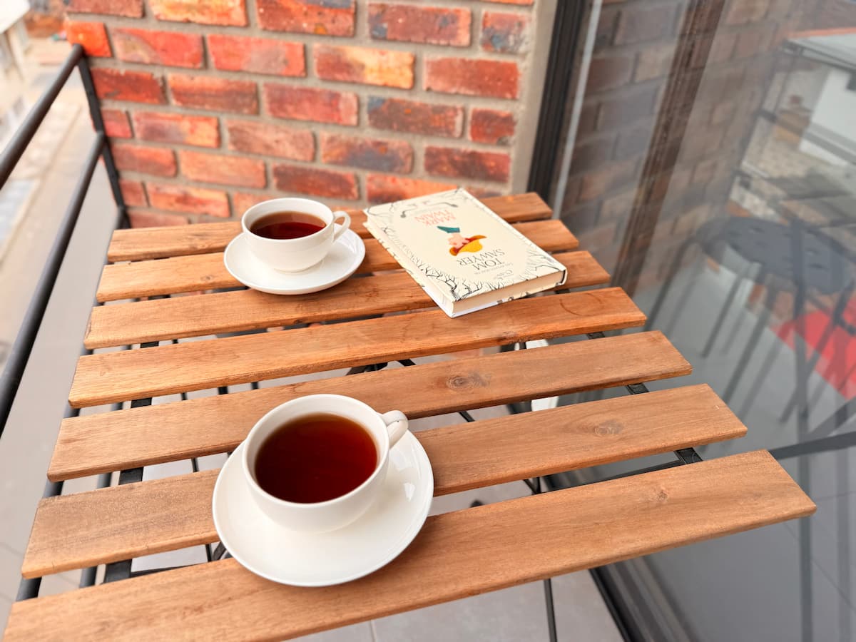 Dos tazas de té y un libro sobre la mesa plegable de madera en el balcón