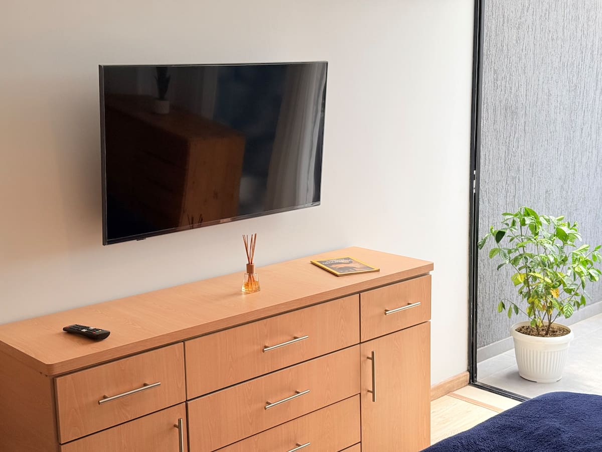 Televisor sobre una cómoda larga de madera junto al ventanal de la terraza